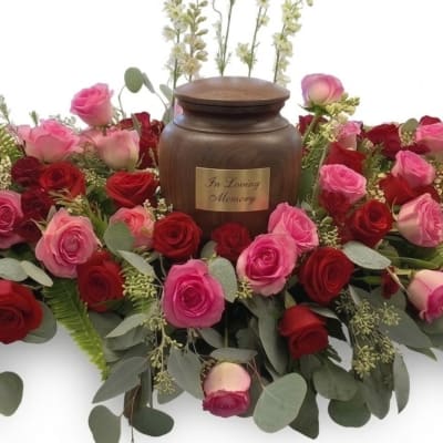 Pink and red roses arranged around a memorial urn