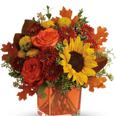 Autumn bouquet with sunflowers, roses, and mums in an orange glass vase