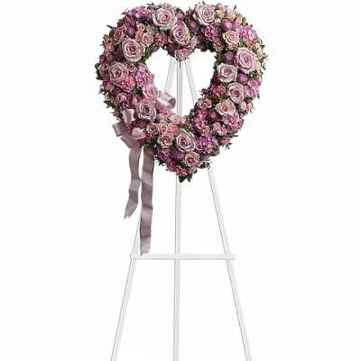 Heart-shaped pink rose wreath on a white easel with ribbon