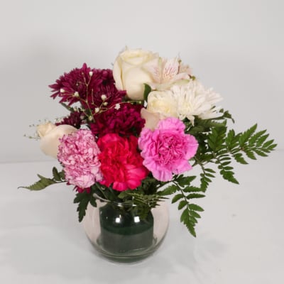 Mixed bouquet of roses, carnations, and chrysanthemums in a glass vase