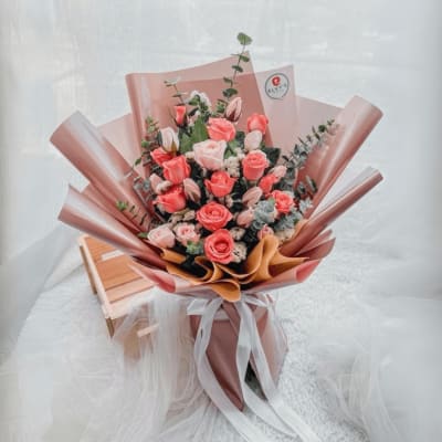 Pink rose bouquet wrapped in blush and brown paper with a white ribbon