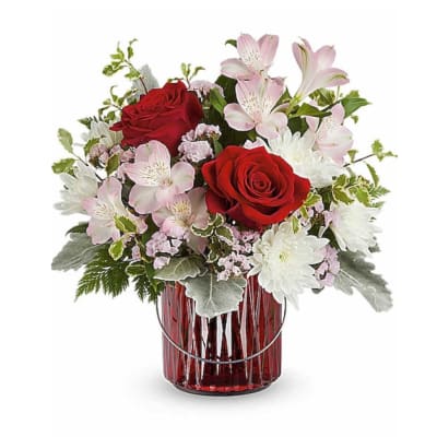 Red roses and pink-white flowers arranged in a red glass vase