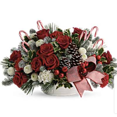 Red roses and holiday greenery in a white bowl with candy canes and ribbon