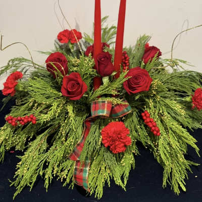 Red roses and carnations arranged with candles and plaid ribbon.