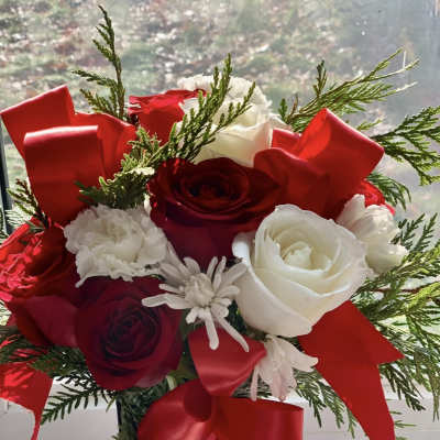 Bouquet of red and white roses with red ribbon in a tall vase
