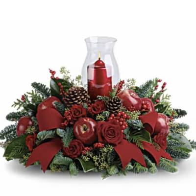 Red candle in a glass hurricane surrounded by roses and pinecones