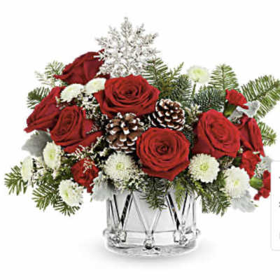 Red roses and white flowers in a clear glass vase with pinecones