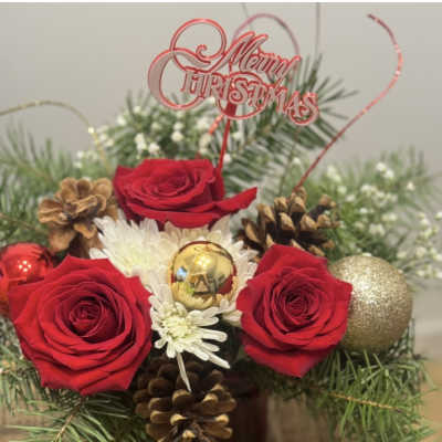 Christmas arrangement with red roses, white daisies, pinecones, and ornaments