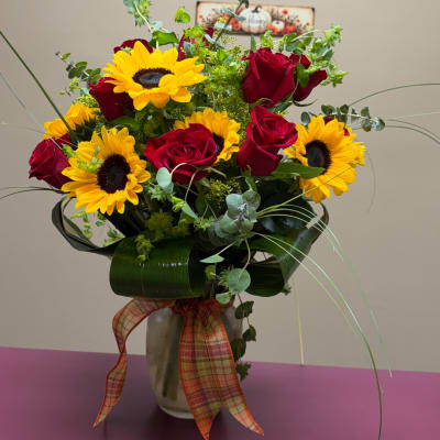 Bouquet of red roses and yellow sunflowers in a vase