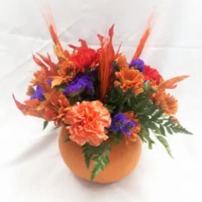 Orange and purple floral arrangement in a round pumpkin-shaped container