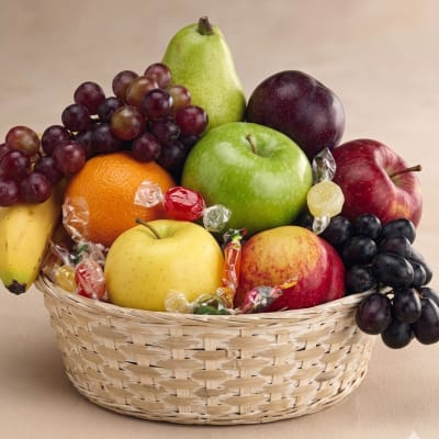 Fruit basket with apples, pears, grapes, and candy in a woven basket