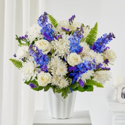 White and blue mixed flower arrangement in a white vase