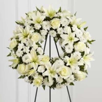 White floral wreath on a black easel stand