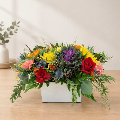 Mixed flower arrangement in a white rectangular box with red roses and yellow blooms
