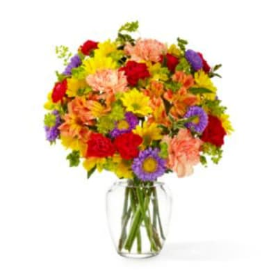 Mixed bouquet of colorful flowers in a clear glass vase