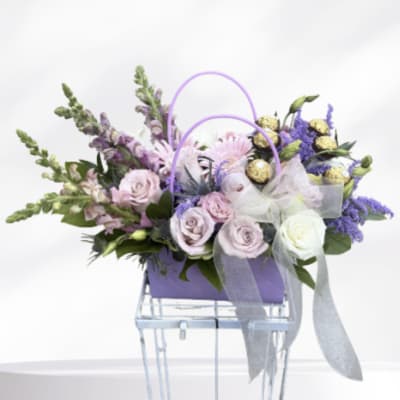 Lavender and white floral arrangement in a purple handled basket