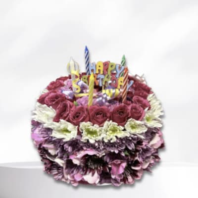 Birthday cake made of flowers with candles and a "Happy Birthday" topper