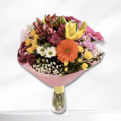Mixed bouquet with gerbera daisies, lilies, and small roses in a glass vase