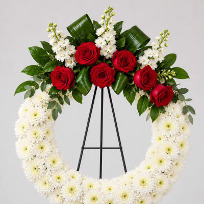 Red roses and white flowers arranged on a standing wreath easel