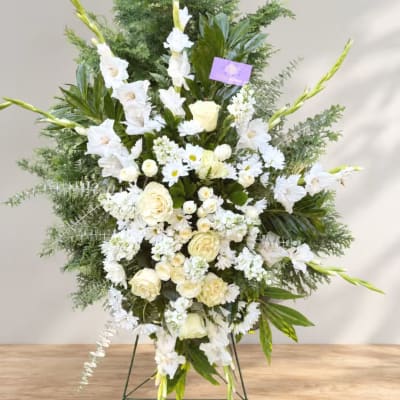 Large white floral standing spray with roses and gladiolus on an easel