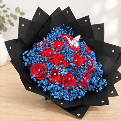 Bouquet of red roses and blue filler flowers wrapped in black paper