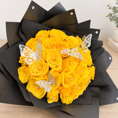Bouquet of yellow roses wrapped in black paper with butterfly decorations