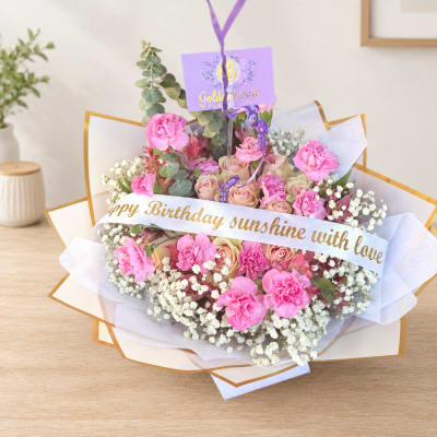 Pink rose bouquet with a birthday ribbon and purple tag