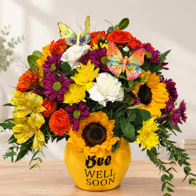 Colorful bouquet in a yellow vase with butterflies and "Bee Well Soon" text