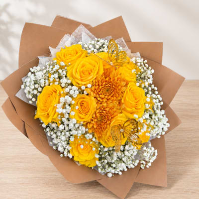 Yellow roses and orange mums with white baby's breath in brown paper wrap