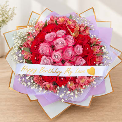 Bouquet of red and pink roses with a birthday ribbon