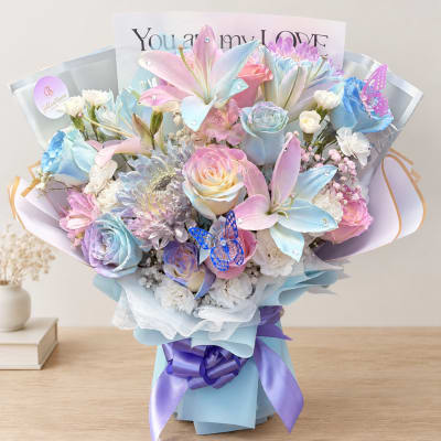 Pastel bouquet of roses and lilies with a purple ribbon and butterfly accents