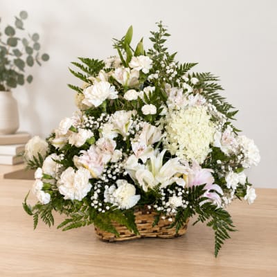 White floral arrangement in a wicker basket with mixed blooms