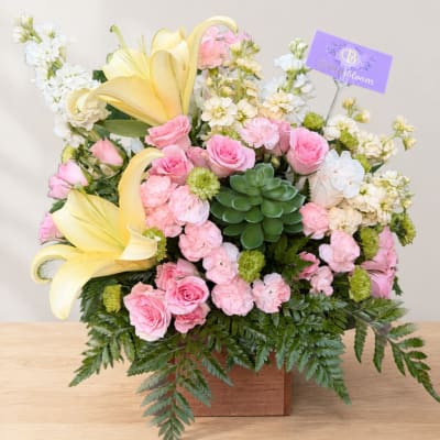 Pink roses and yellow lilies in a wooden box with a succulent accent