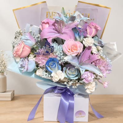 Pastel bouquet of lilies and roses in a gift box with a purple ribbon