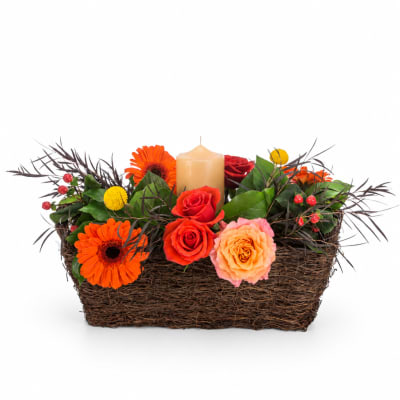 Basket arrangement with roses, gerbera daisies, and a candle