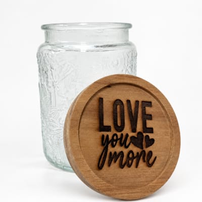 Clear glass jar with a wooden lid engraved "Love you more"