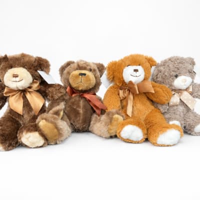 Four plush teddy bears with ribbon bows on a white background