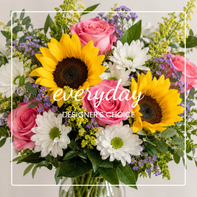 Bouquet of pink roses, sunflowers, and white daisies in a glass vase