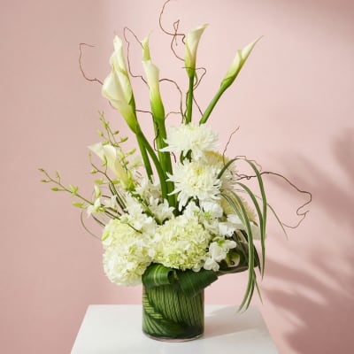 White floral arrangement with calla lilies and chrysanthemums in a glass vase