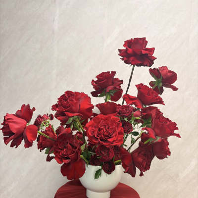 Red roses arranged in a white vase on a draped table