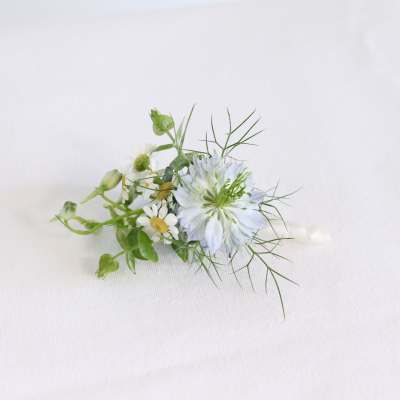 Small white flower boutonniere with green accents