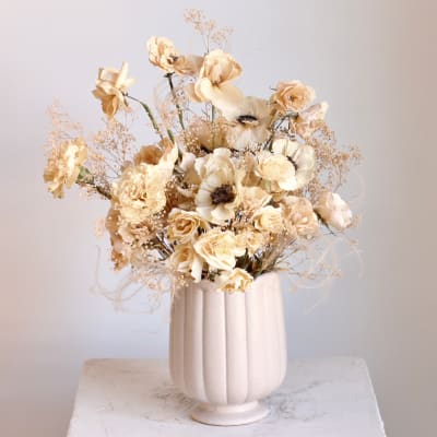 Cream floral arrangement in a ribbed white vase