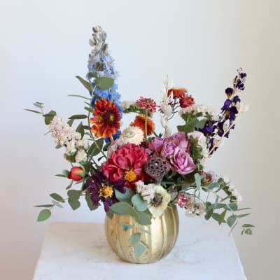 Mixed bouquet in a gold vase with pink, purple, blue, and white flowers