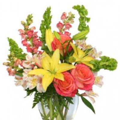 Bouquet of yellow lilies, pink roses, and snapdragons in a glass vase