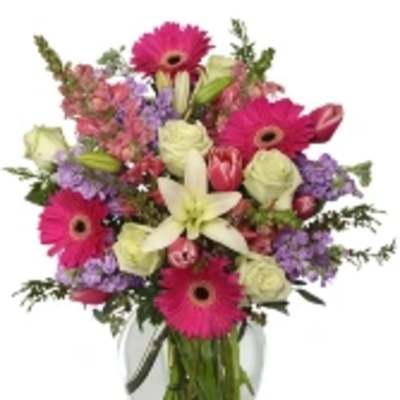 Mixed bouquet with pink gerbera daisies, white lilies, and roses in a glass vase