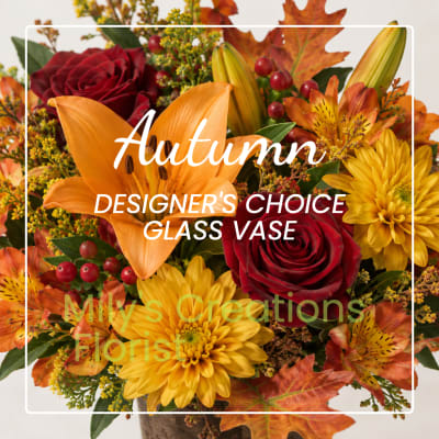 Autumn bouquet with red roses, orange lilies, and yellow daisies in a glass vase
