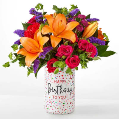 Bouquet of orange lilies and pink roses in a birthday vase