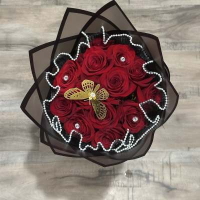 Bouquet of red roses wrapped in black paper with pearl trim
