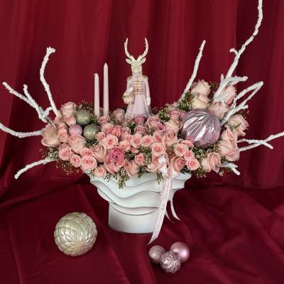 Pink rose arrangement in a white vase with candles and decorative ornaments