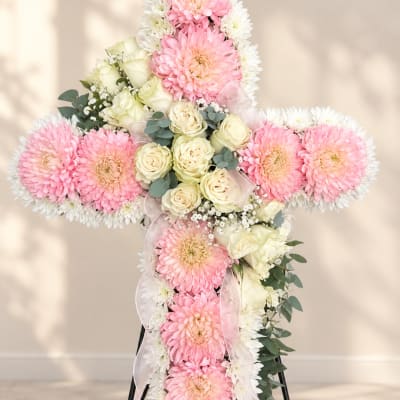 Cross-shaped floral arrangement with pink and white flowers and ribbon